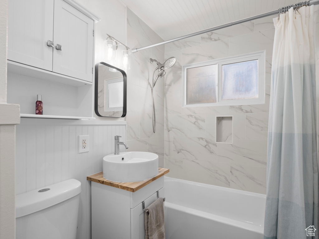 Bathroom with shower / bath combo with shower curtain, toilet, and vanity
