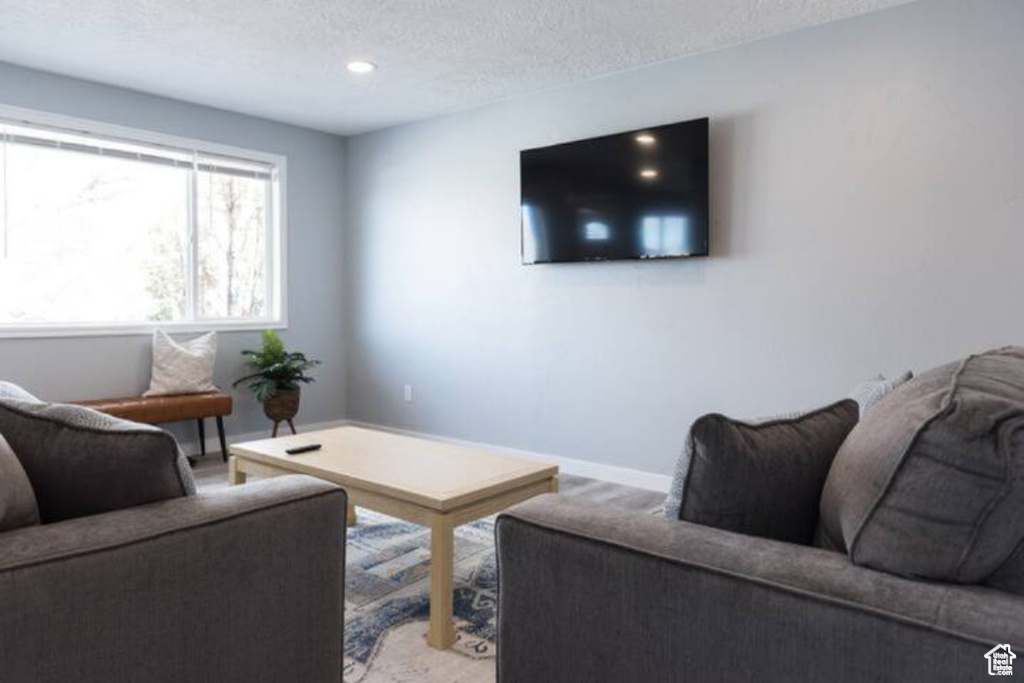 Living room featuring a textured ceiling, baseboards, recessed lighting, and carpet floors