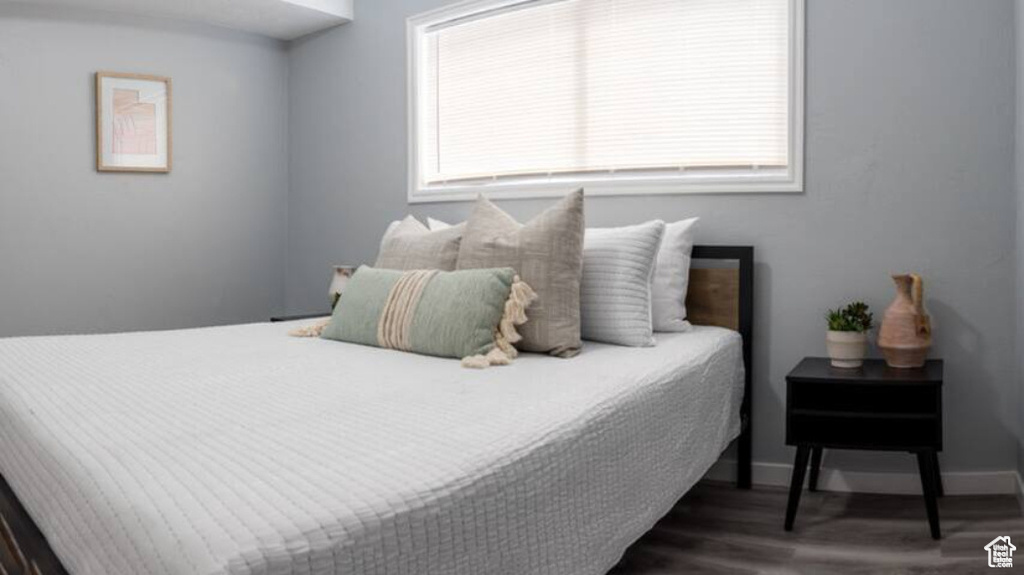 Bedroom with wood finished floors, multiple windows, and baseboards