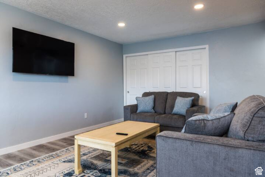 Living area with wood finished floors, recessed lighting, and baseboards