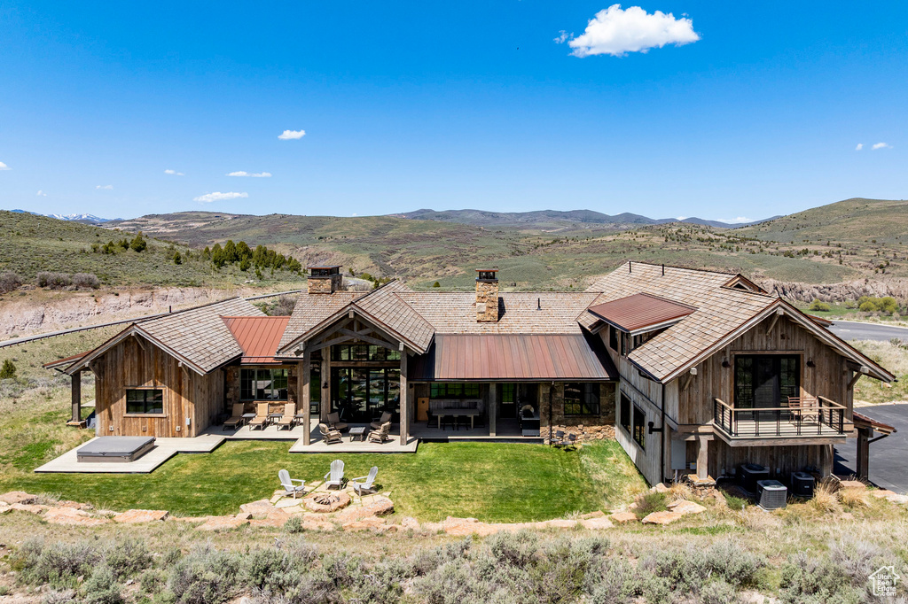 Rear view of property with an outdoor fire pit, a chimney, a mountain view, a patio, and metal roof