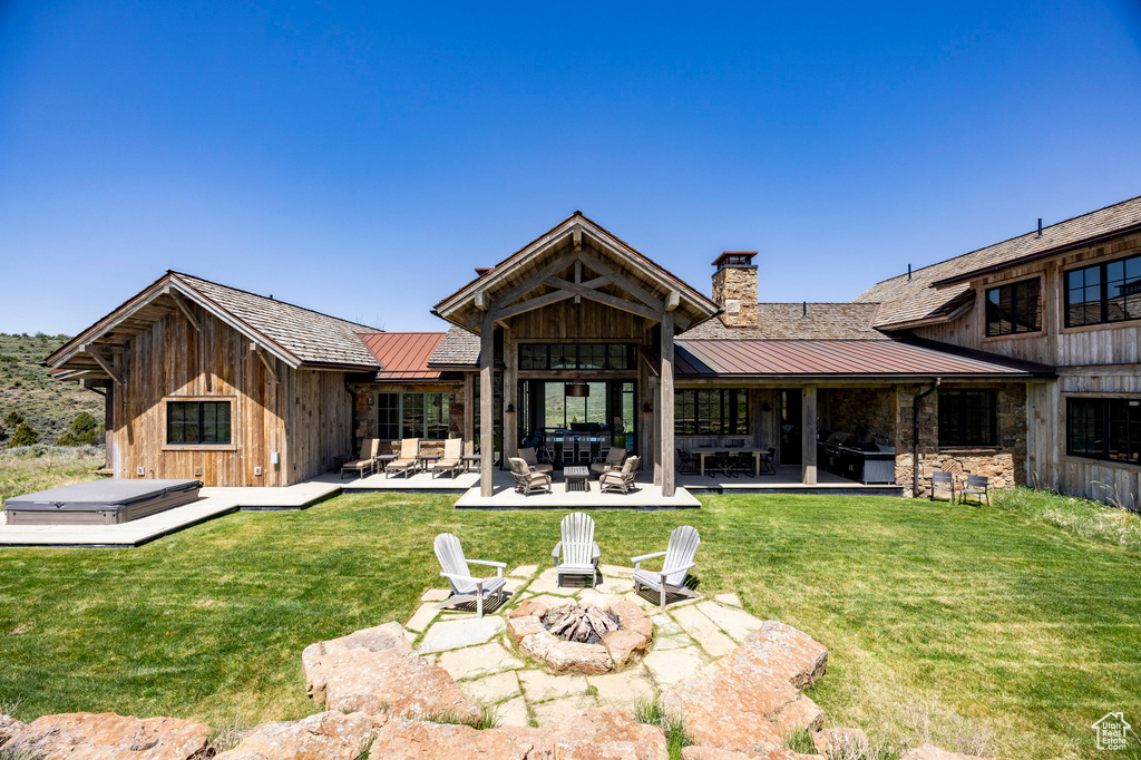 Rear view of property featuring a standing seam roof, an outdoor living space with a fire pit, metal roof, and a chimney