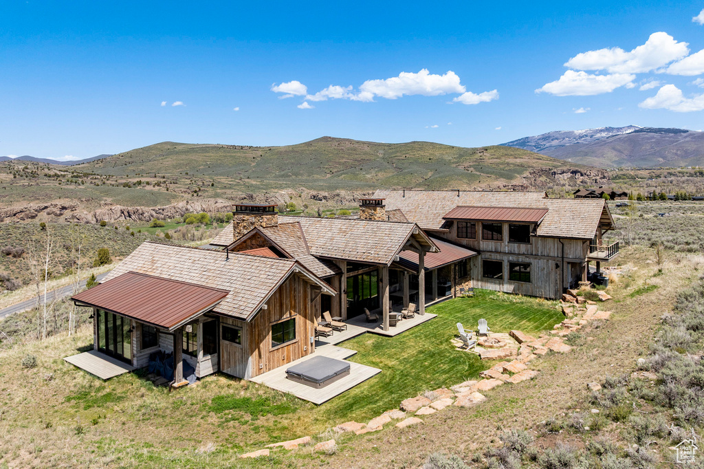 Rear view of house featuring a chimney, a mountain view, a yard, a patio area, and board and batten siding