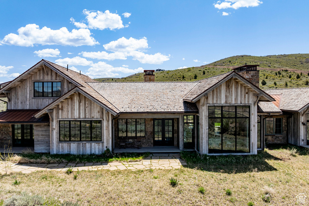 Back of house with a chimney, french doors, a mountain view, a yard, and a patio area