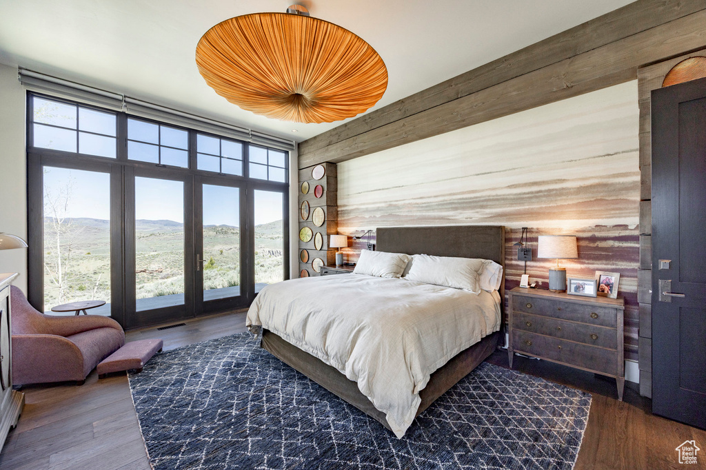 Bedroom with wood walls, a mountain view, and wood finished floors