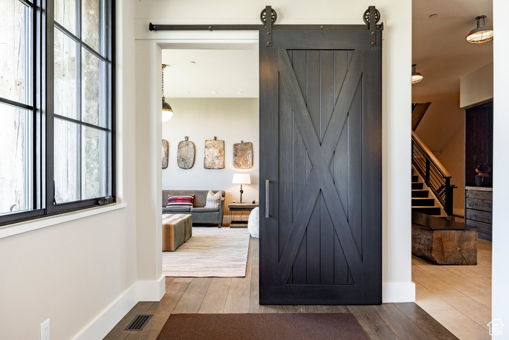 Hall featuring a barn door, wood finished floors, stairway, and baseboards