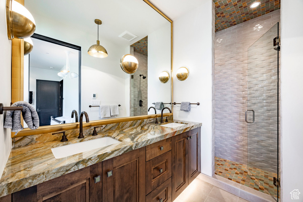 Bathroom with a shower stall, double vanity, and tile patterned flooring