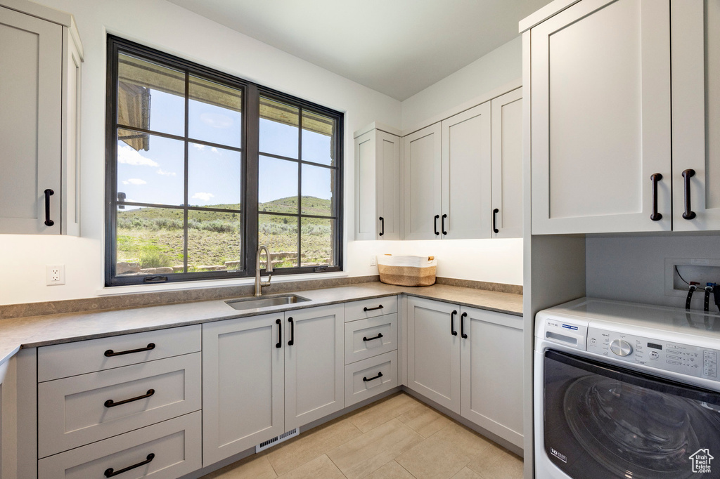 Clothes washing area with washer / dryer, cabinet space, and light tile patterned floors