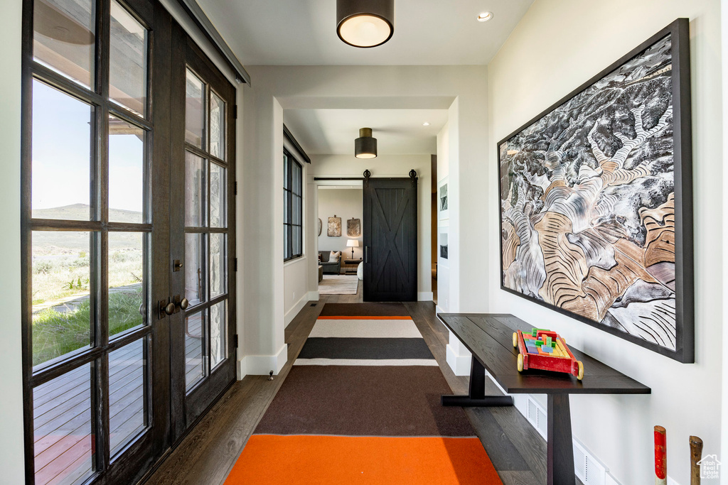 Hallway featuring french doors, dark wood-style floors, a barn door, baseboards, and recessed lighting