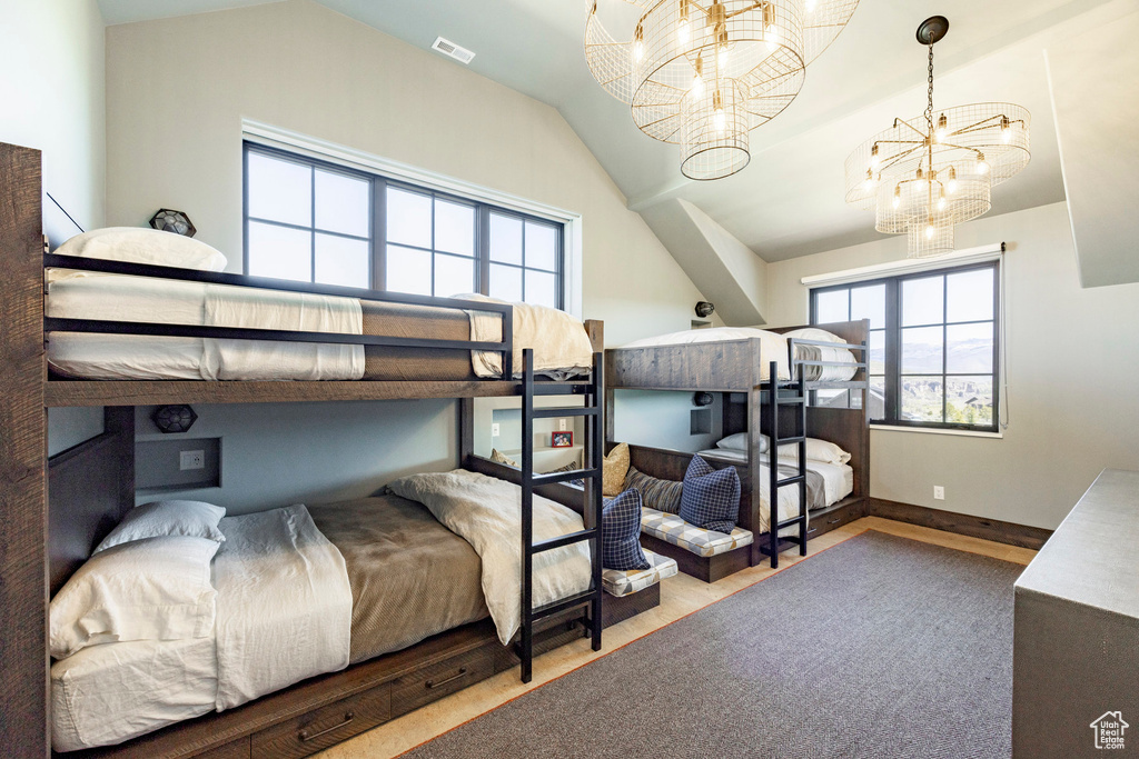Bedroom featuring a chandelier, lofted ceiling, wood finished floors, and baseboards