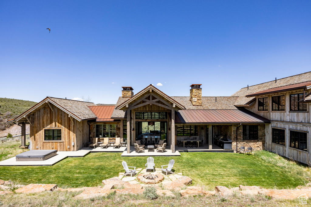 Rear view of house with a standing seam roof, a chimney, metal roof, and a patio area