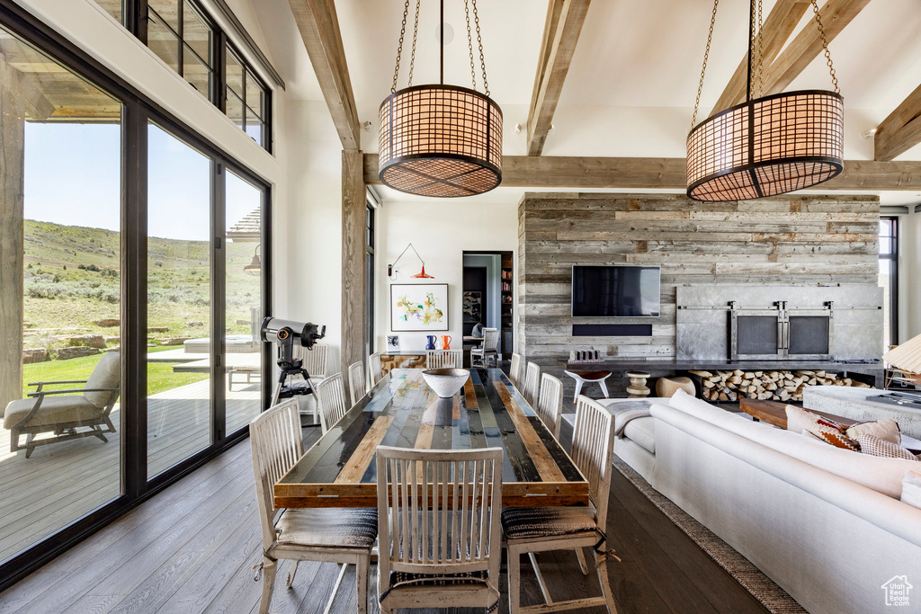 Dining room with hardwood / wood-style floors, a high ceiling, beamed ceiling, a mountain view, and a fireplace
