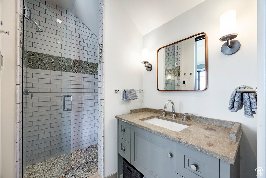 Bathroom with a shower stall, vanity, and vaulted ceiling