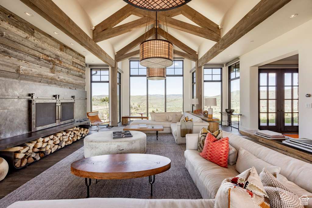 Living room with high vaulted ceiling, beamed ceiling, wood finished floors, a barn door, and recessed lighting
