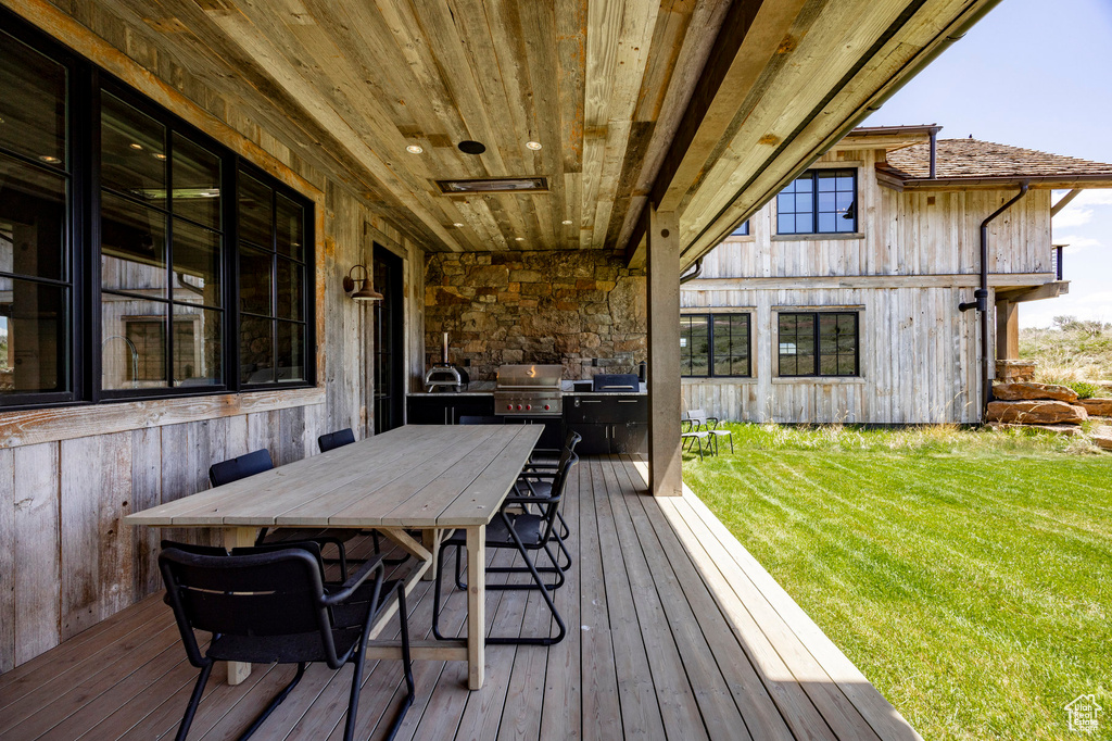 Deck with a lawn, a grill, outdoor dining space, and a sink