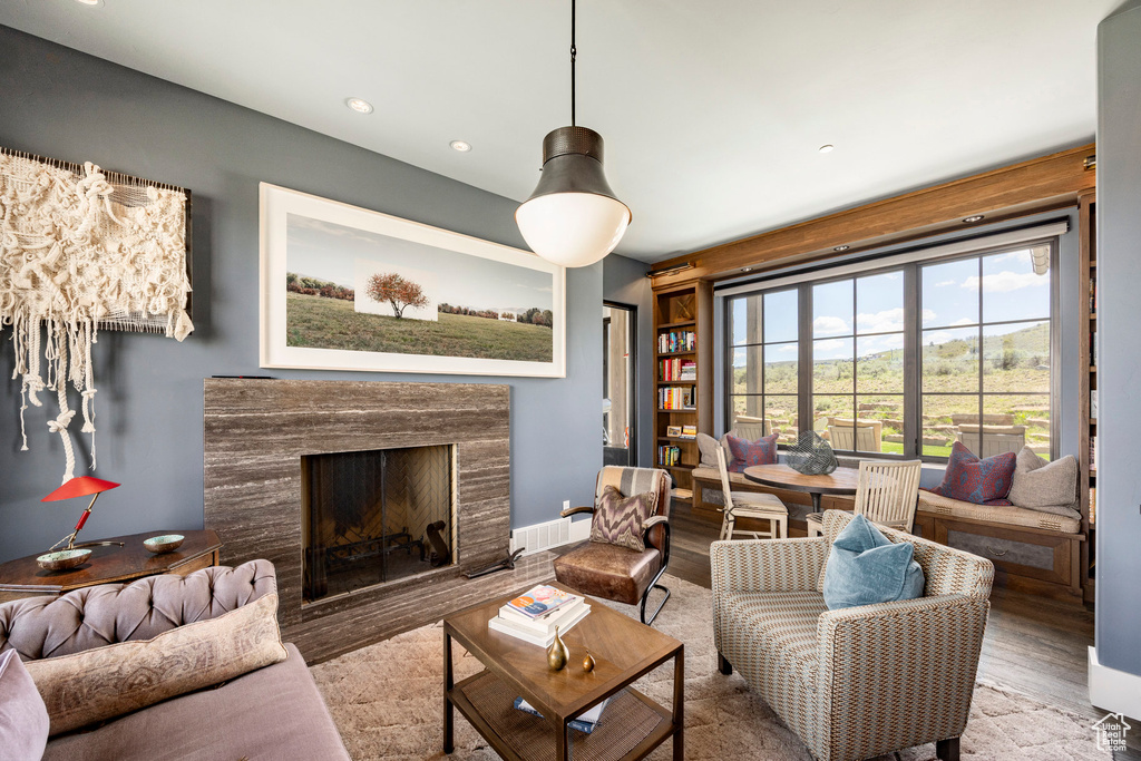 Living area with wood finished floors, a high end fireplace, and recessed lighting