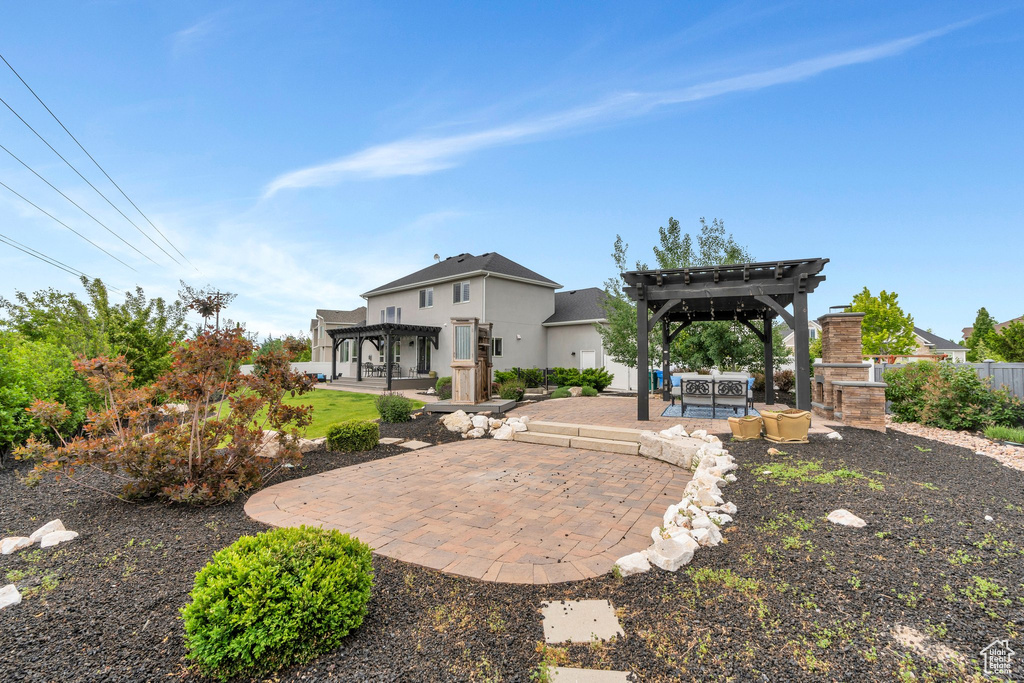 Rear view of property featuring a pergola, a patio, and stucco siding