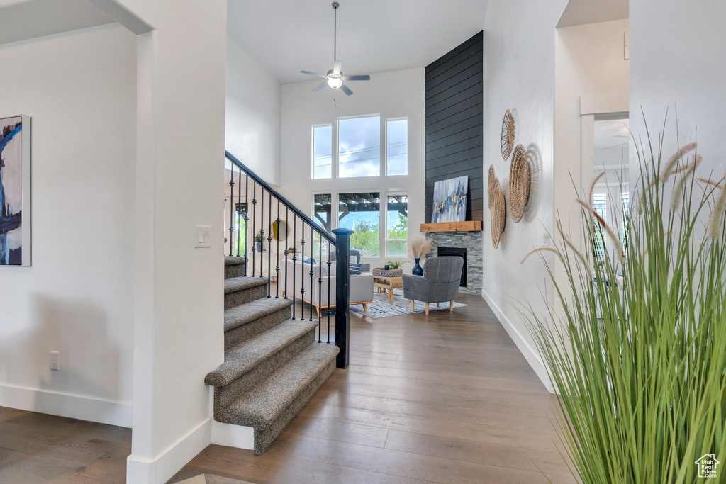 Stairs with a ceiling fan, baseboards, hardwood / wood-style floors, a high ceiling, and a fireplace