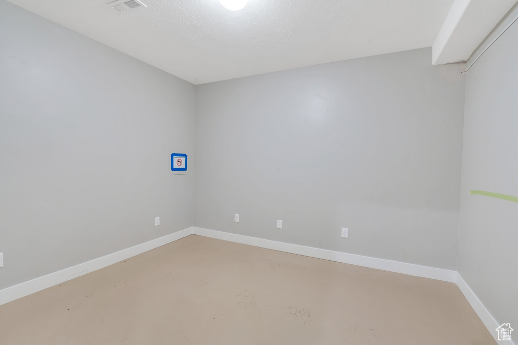 Empty room featuring finished concrete flooring and baseboards