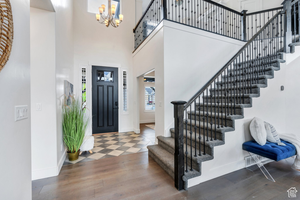 Foyer with a chandelier, baseboards, stairs, a high ceiling, and wood finished floors