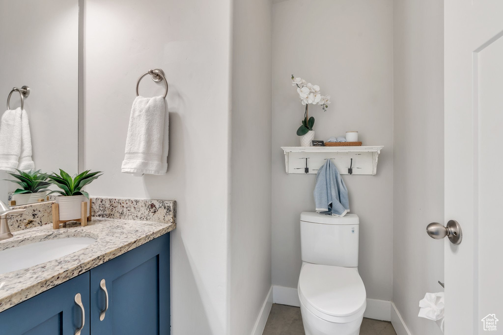 Bathroom featuring baseboards, vanity, toilet, and tile patterned flooring