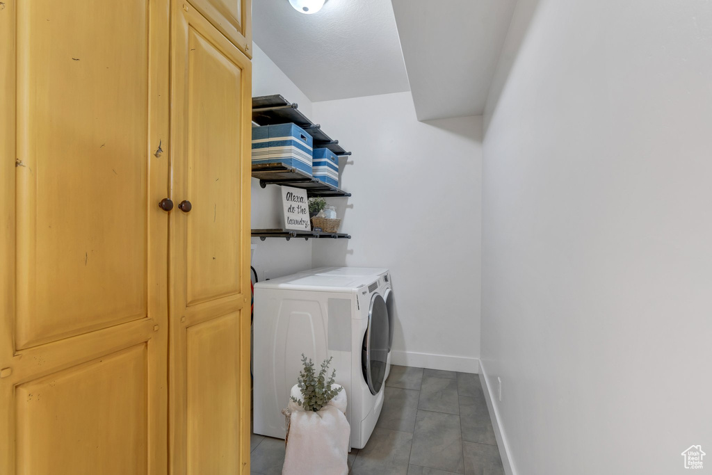 Laundry area featuring washing machine and dryer, baseboards, tile patterned floors, and cabinet space