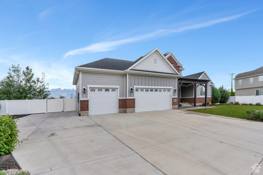 View of front of house featuring a garage, driveway, brick siding, and board and batten siding
