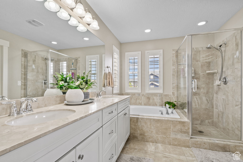 Bathroom featuring a stall shower, a garden tub, double vanity, recessed lighting, and tile patterned floors