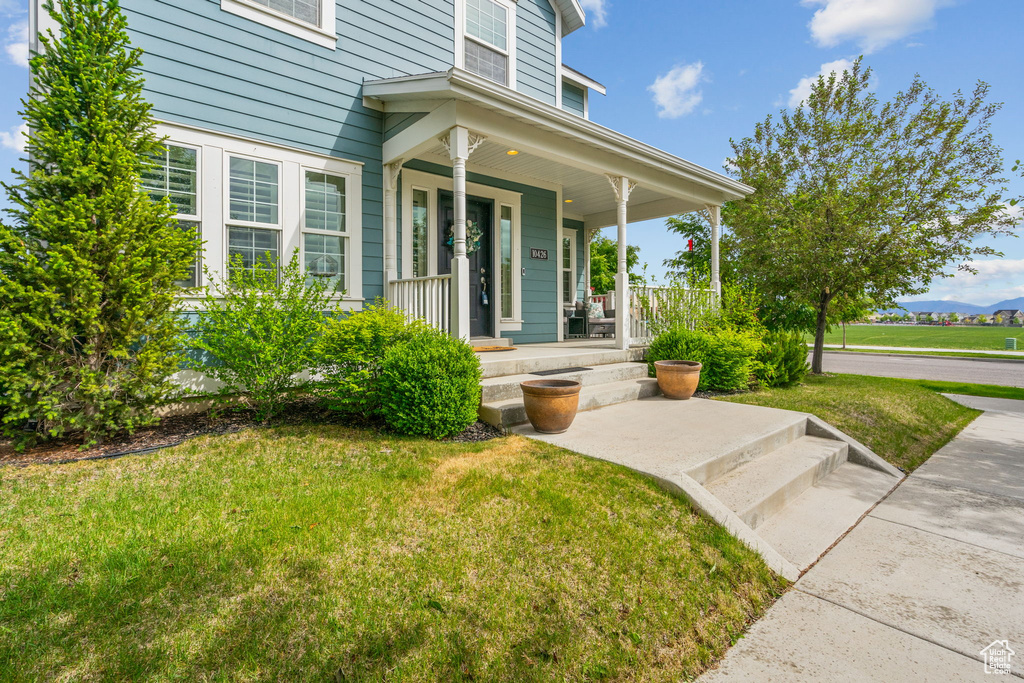 Entrance to property featuring covered porch and a yard