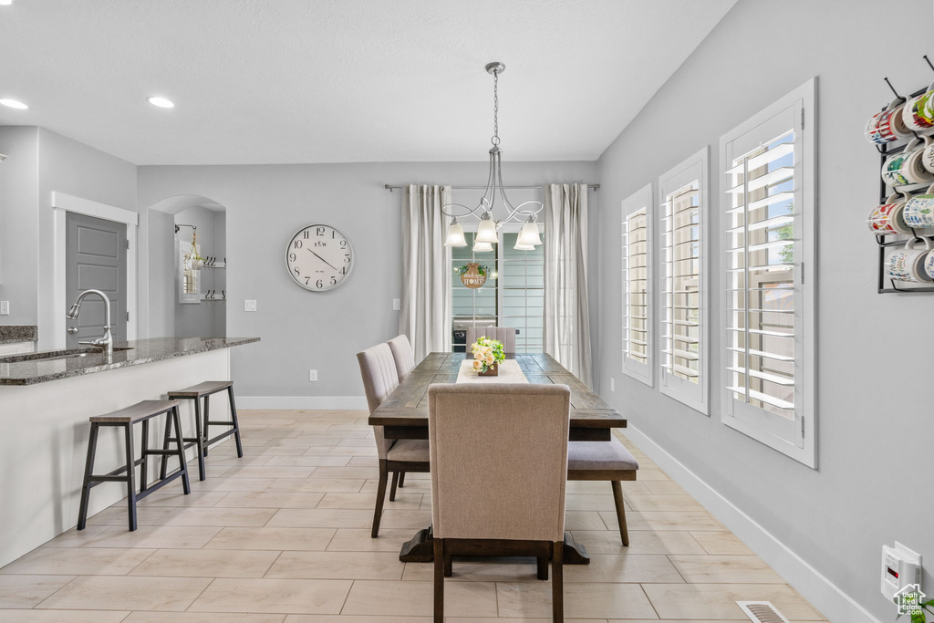 Dining area with arched walkways, recessed lighting, a chandelier, baseboards, and light tile patterned flooring