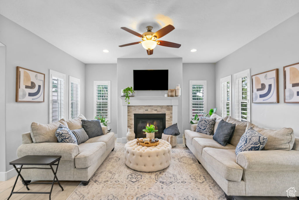 Living area featuring plenty of natural light, a ceiling fan, a stone fireplace, wood finished floors, and recessed lighting