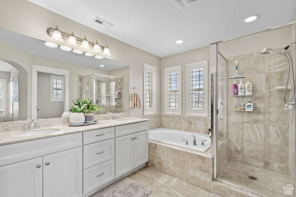 Bathroom featuring a shower stall, a garden tub, double vanity, tile patterned flooring, and recessed lighting