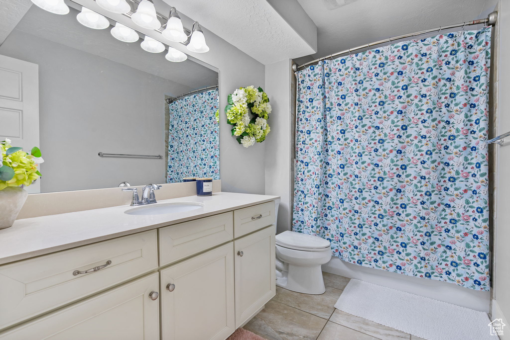 Full bathroom with tile patterned floors, toilet, vanity, and shower / bath combo