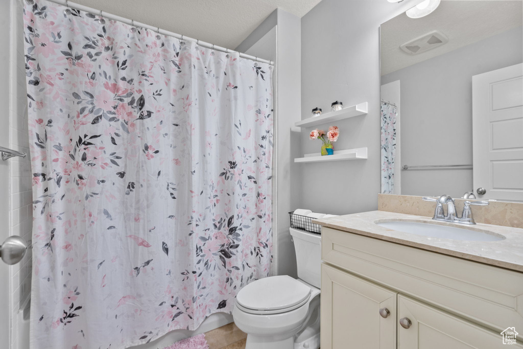Bathroom with toilet, vanity, and curtained shower