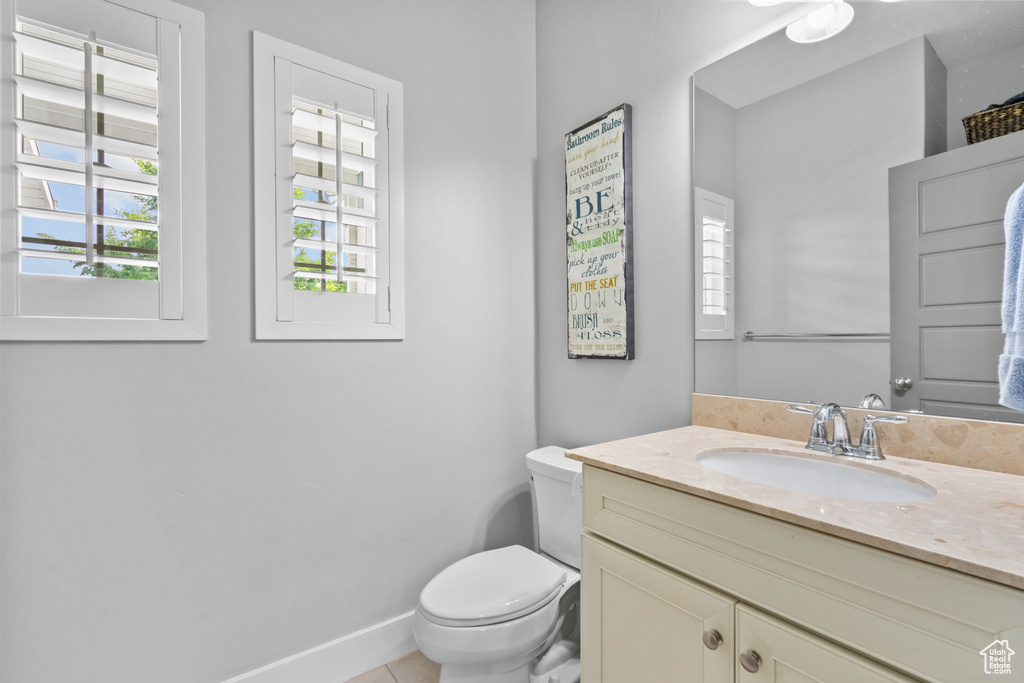 Bathroom with toilet, vanity, and tile patterned floors