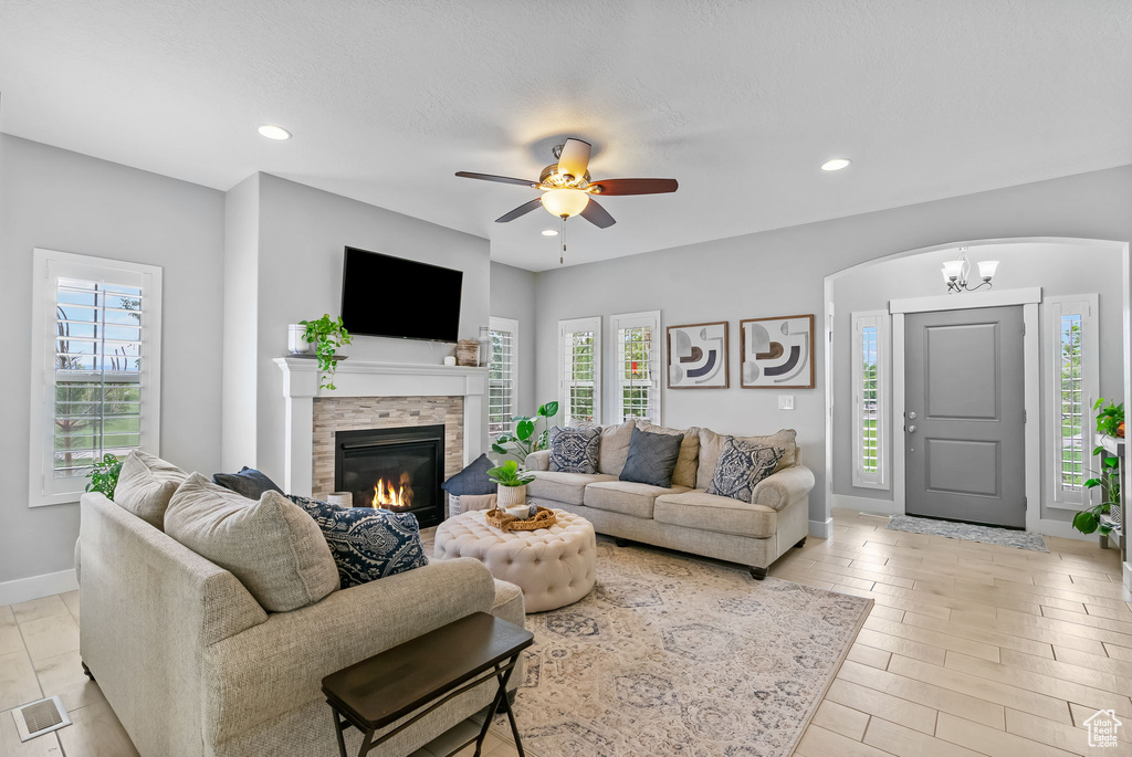 Living room with plenty of natural light, a glass covered fireplace, baseboards, a ceiling fan, and recessed lighting