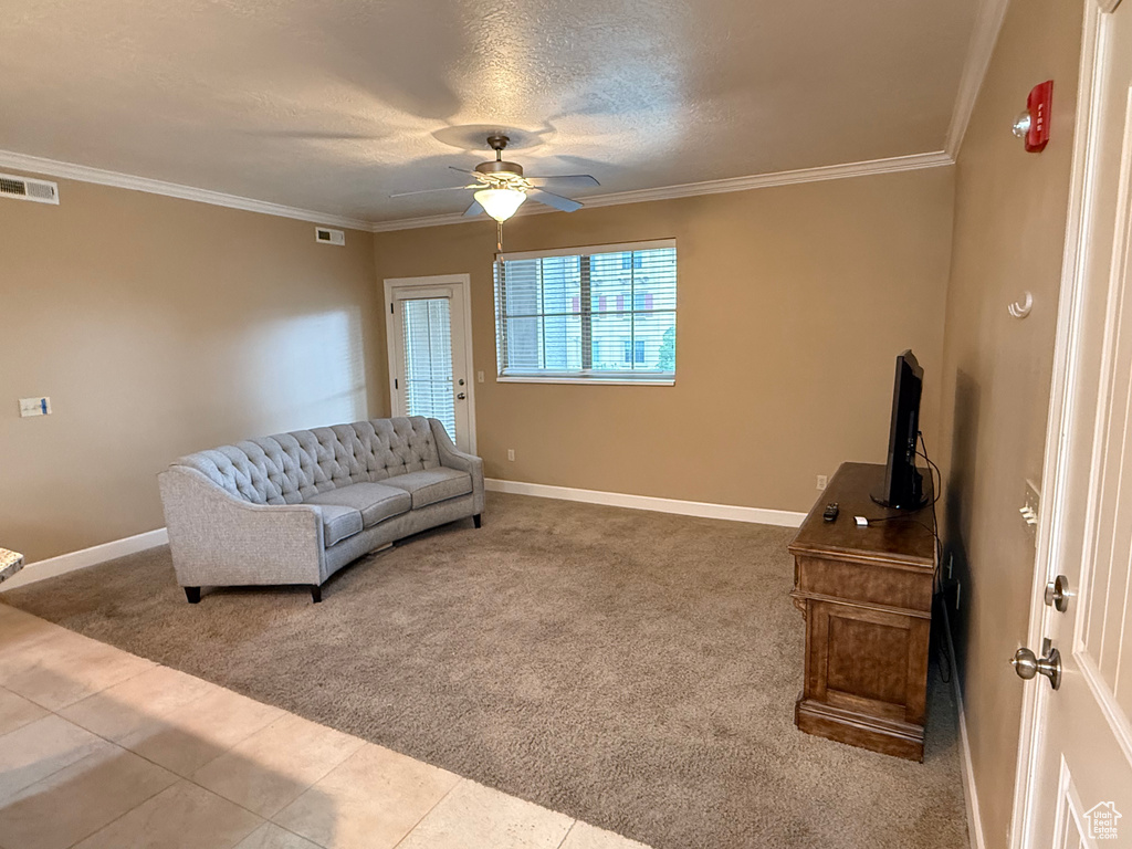 Sitting room with carpet flooring, a ceiling fan, baseboards, ornamental molding, and tile patterned floors