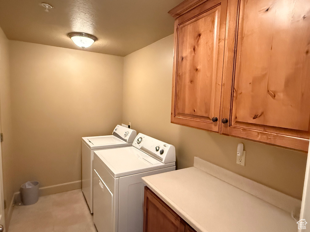 Washroom with cabinet space, washing machine and clothes dryer, and baseboards