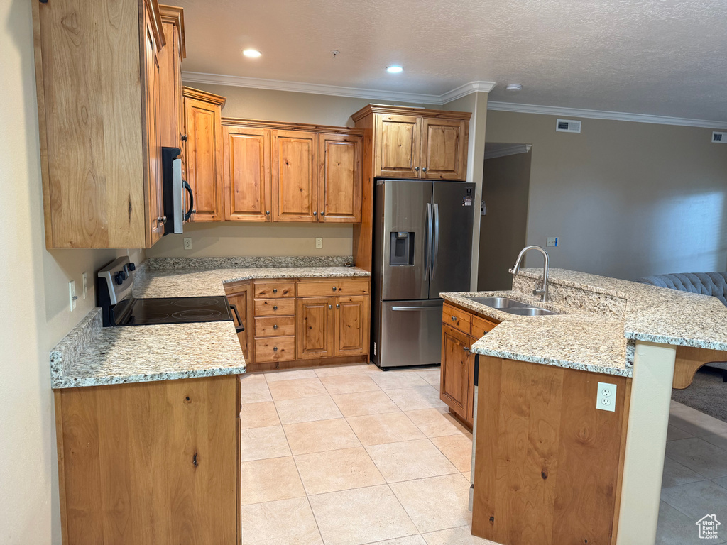 Kitchen featuring stainless steel refrigerator with ice dispenser, range with electric cooktop, a sink, a breakfast bar area, and brown cabinetry