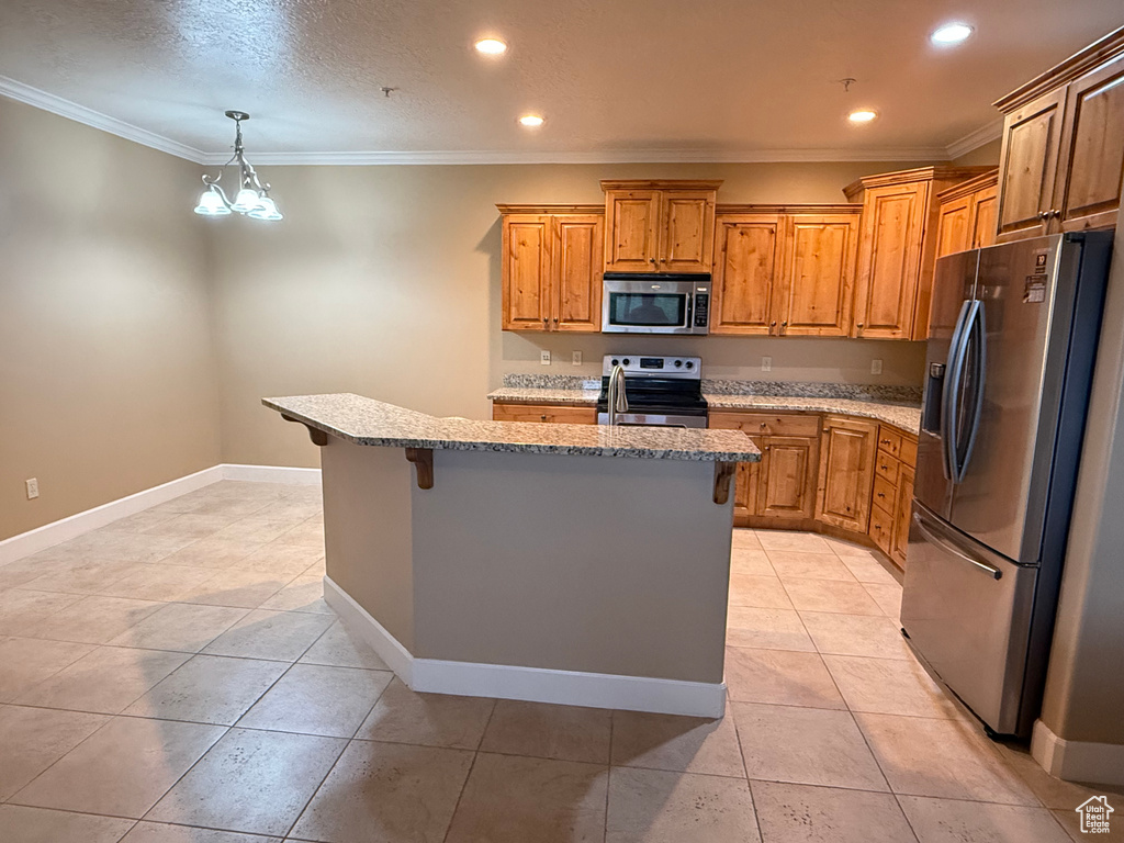 Kitchen with stainless steel appliances, a kitchen breakfast bar, light tile patterned floors, crown molding, and light stone counters