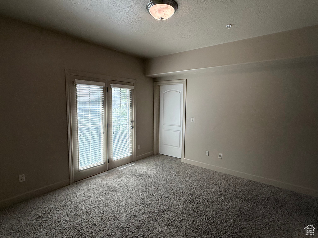 Empty room featuring carpet, a textured ceiling, and baseboards