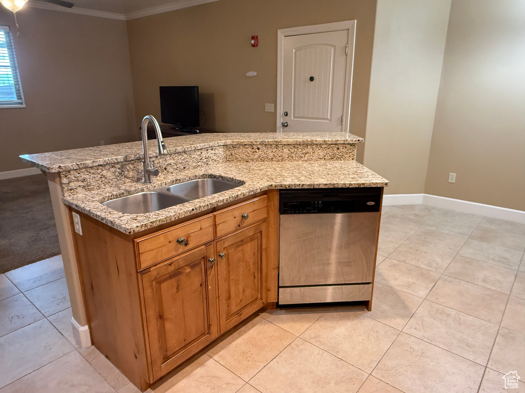 Kitchen featuring stainless steel dishwasher, a sink, ornamental molding, light tile patterned floors, and a center island with sink