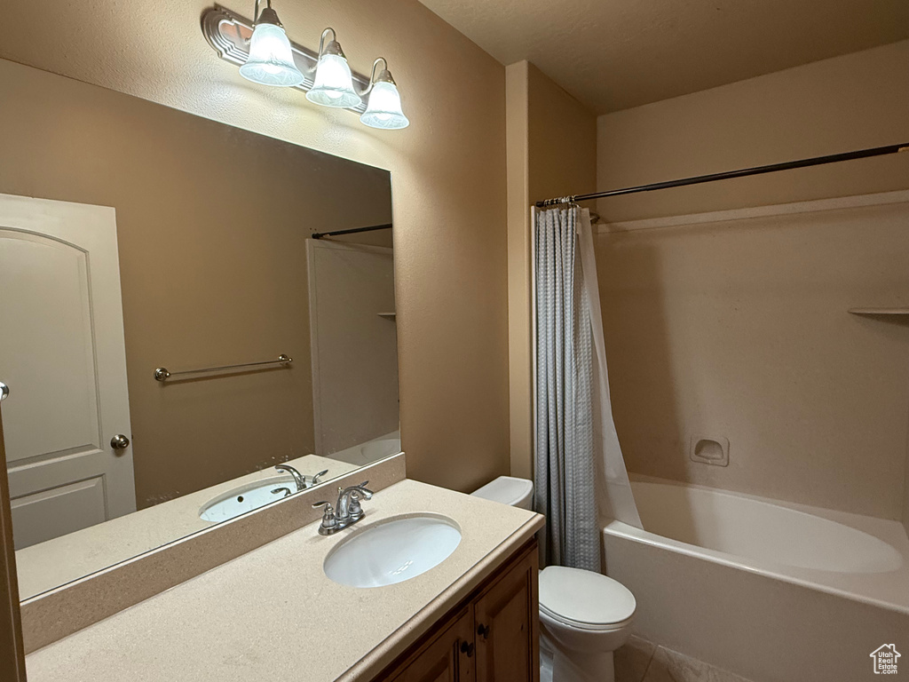 Bathroom with toilet, vanity, tile patterned flooring, and shower / tub combo