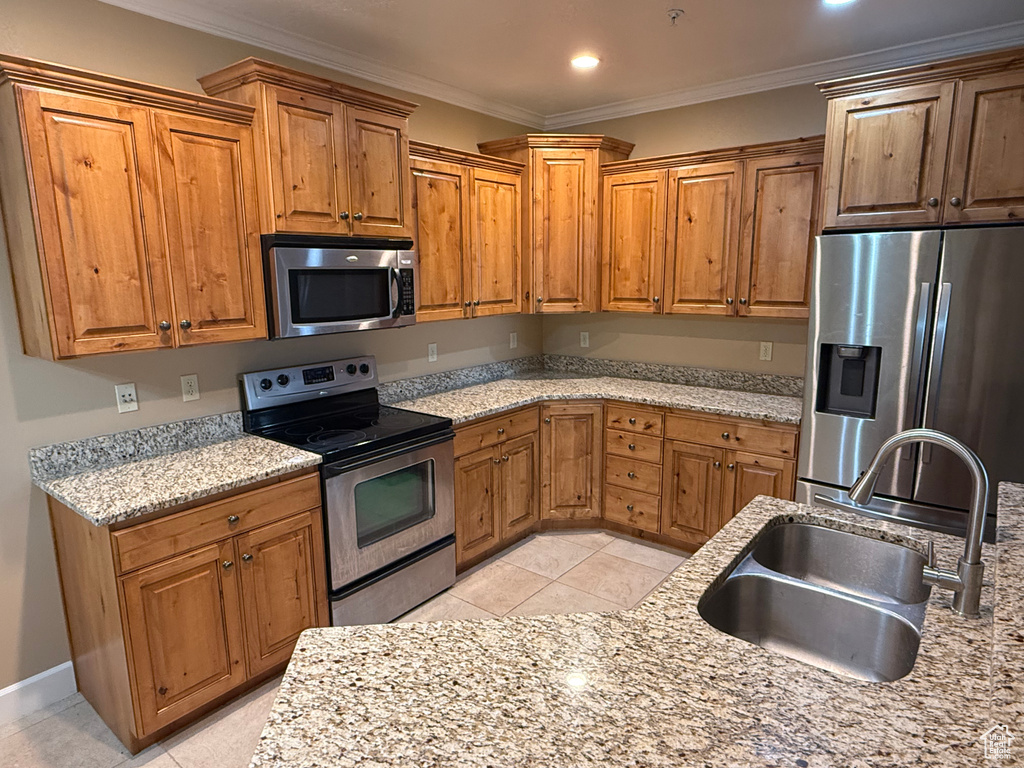 Kitchen featuring stainless steel appliances, a sink, crown molding, brown cabinetry, and light tile patterned floors