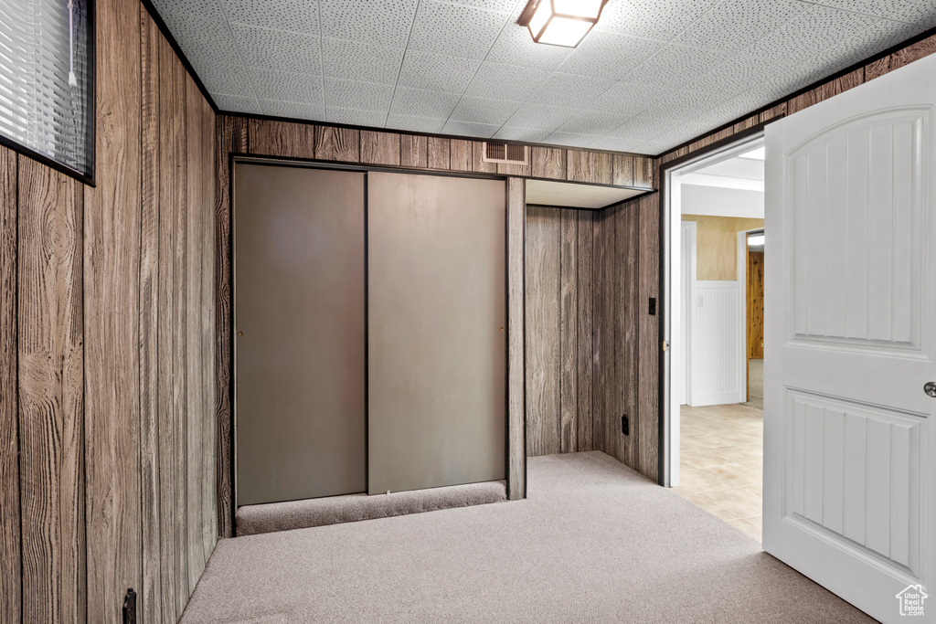 Unfurnished bedroom featuring wood walls, carpet floors, and a closet