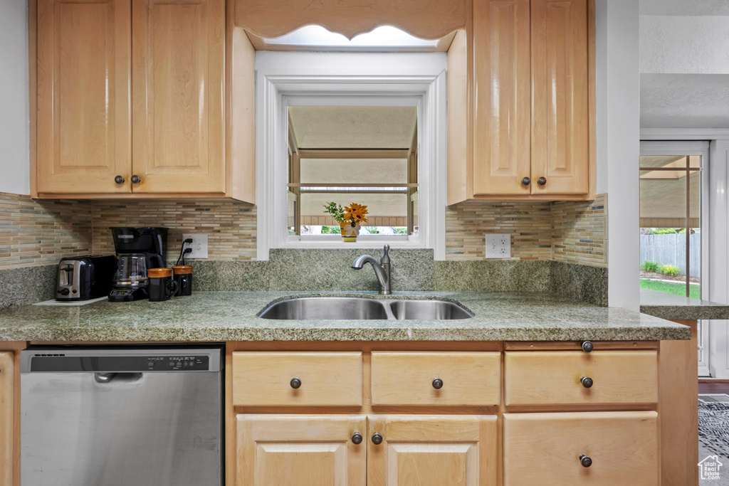Kitchen with dishwasher, a sink, light brown cabinets, and light countertops