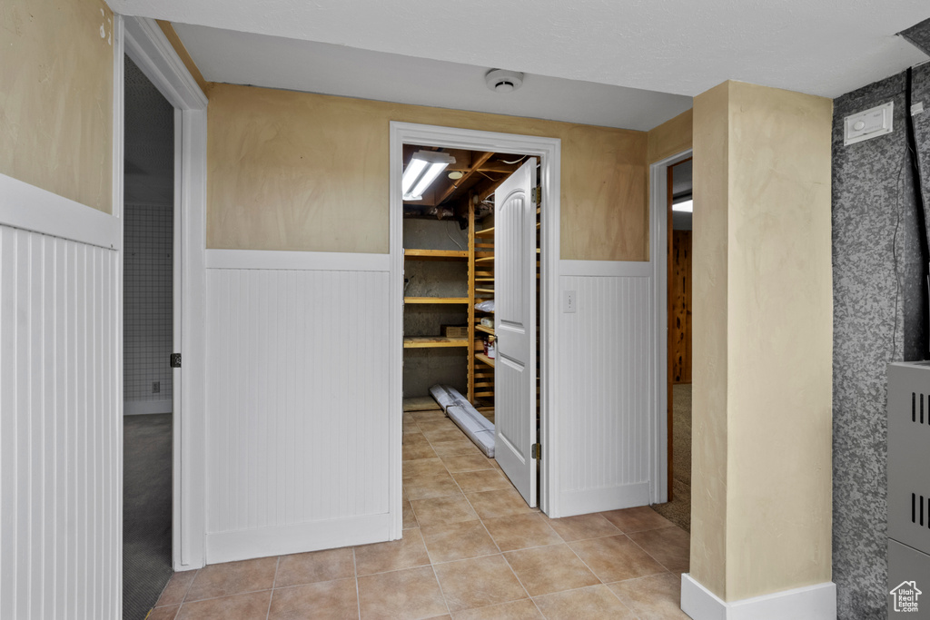 Hall featuring wainscoting and light tile patterned floors