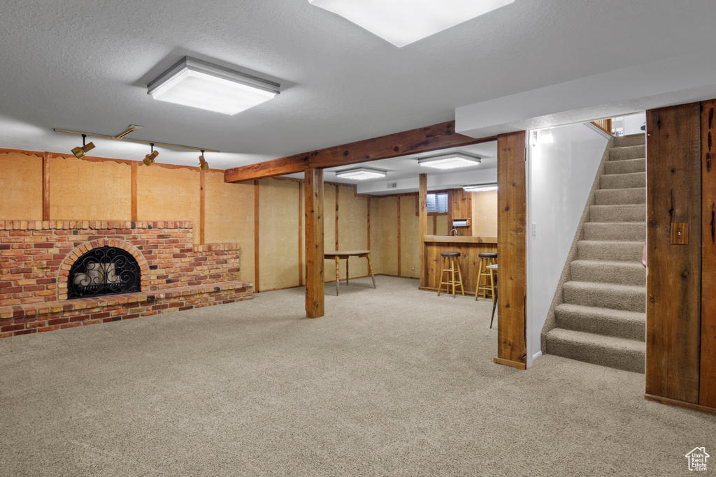 Below grade area featuring a bar, stairs, carpet floors, and a textured ceiling