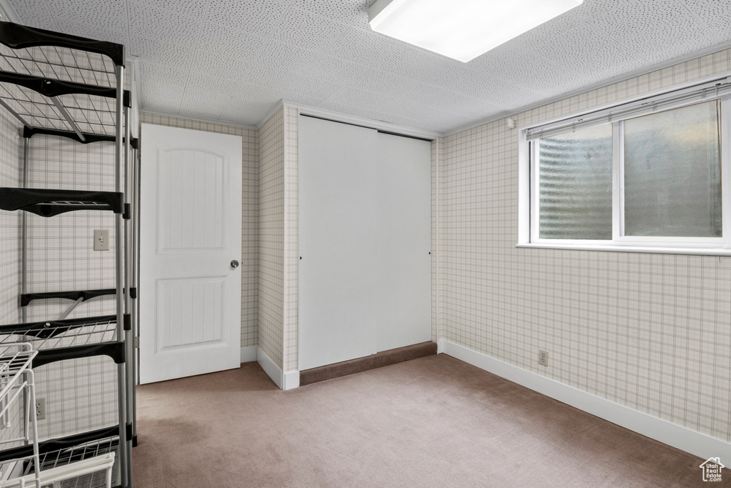 Unfurnished bedroom featuring carpet flooring, a closet, baseboards, a textured ceiling, and wallpapered walls