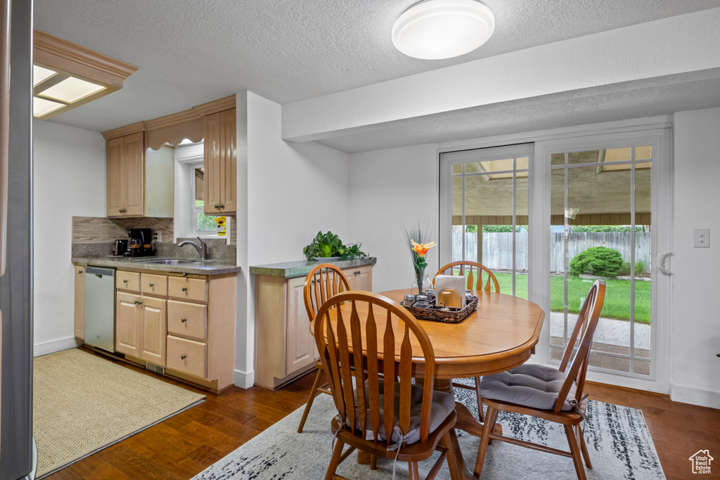 Dining space with a textured ceiling, dark wood finished floors, and baseboards
